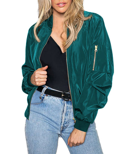 Frau in grüner Bomberjacke, schwarze Bluse, blaue Jeans, modisch, lässiger Stil.