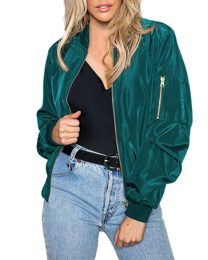 Frau in grüner Bomberjacke aus Satin, schwarze Bluse, blaue Jeans, modisch, lässiger Stil.