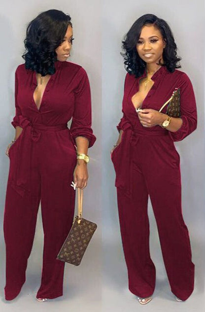 Frau in rotem Jumpsuit mit Gürtel, hält braune Designer-Handtasche, elegante Mode.