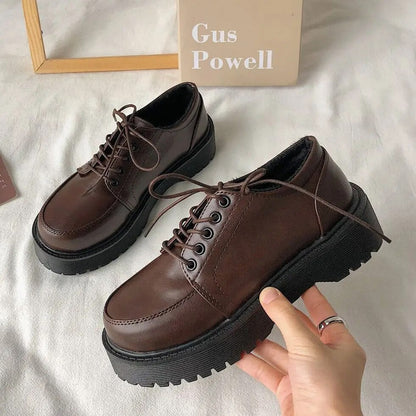 Braune Leder-Damenschuhe mit dicker Sohle, Schnürung, modisch, robust, auf weißem Hintergrund.