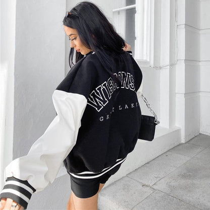 Frau trägt schwarze Collegejacke mit weißen Ärmeln, Schriftzug "WISCONSIN", modisch, urban.