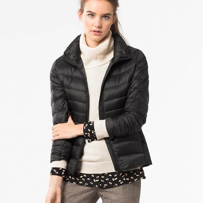 Frau trägt schwarze Daunenjacke, cremefarbenen Rollkragenpullover, modisch, winterlich.