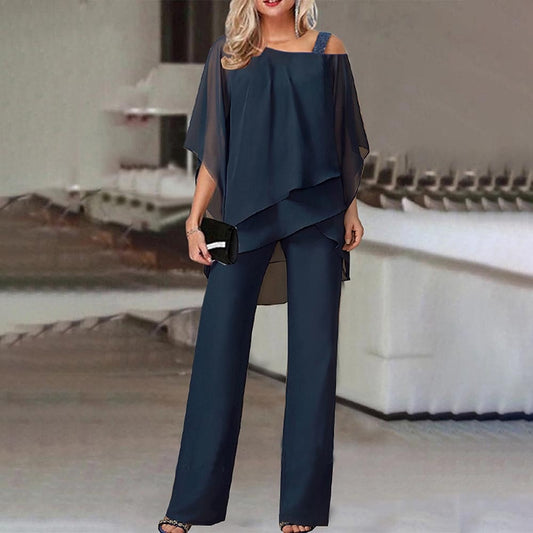 Frau in eleganter, dunkelblauer Chiffon-Hose und Bluse, Abendmode, schulterfrei, mit Clutch.