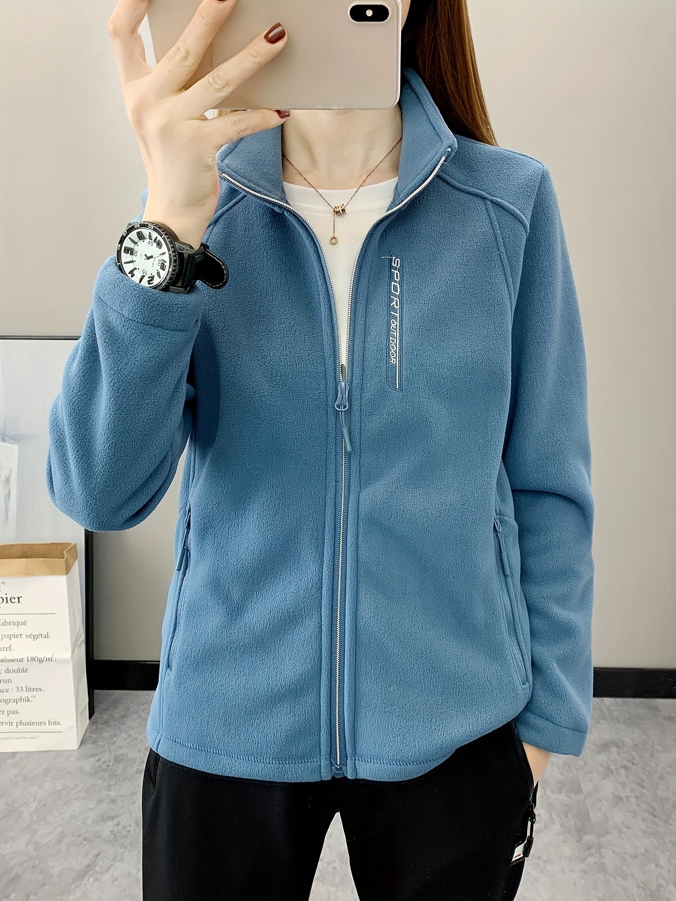 Frau in blauer Fleecejacke mit Reißverschluss, Sportuhr, lässiger Stil, Innenaufnahme.
