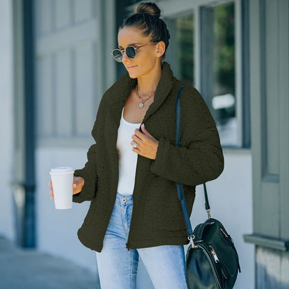 Frau in schwarzer Teddyjacke, Sonnenbrille, Jeans, hält Kaffeebecher, modisch, urban.