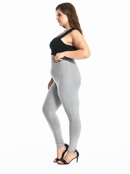 Frau in grauer Leggings und schwarzem Top, seitlich, auf weißem Hintergrund, Modefotografie.