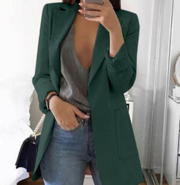 Dame in grünem Blazer, grauem Top und Jeans, hält Smartphone, modisch, modern, elegant.