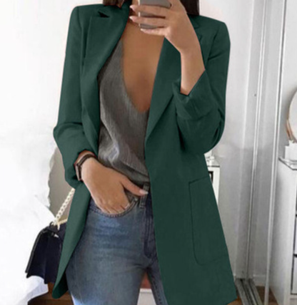 Dame in grünem Blazer, grauem Top und Jeans, hält Smartphone, modisch, modern, elegant.