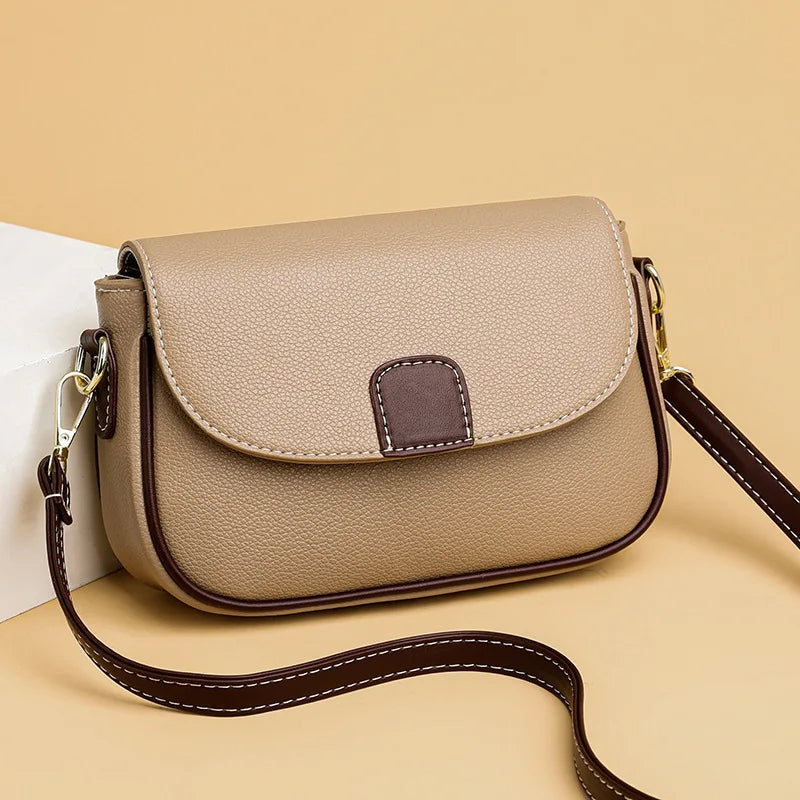Beige Umhängetasche aus Leder mit braunen Akzenten und verstellbarem Riemen, modisch und elegant.