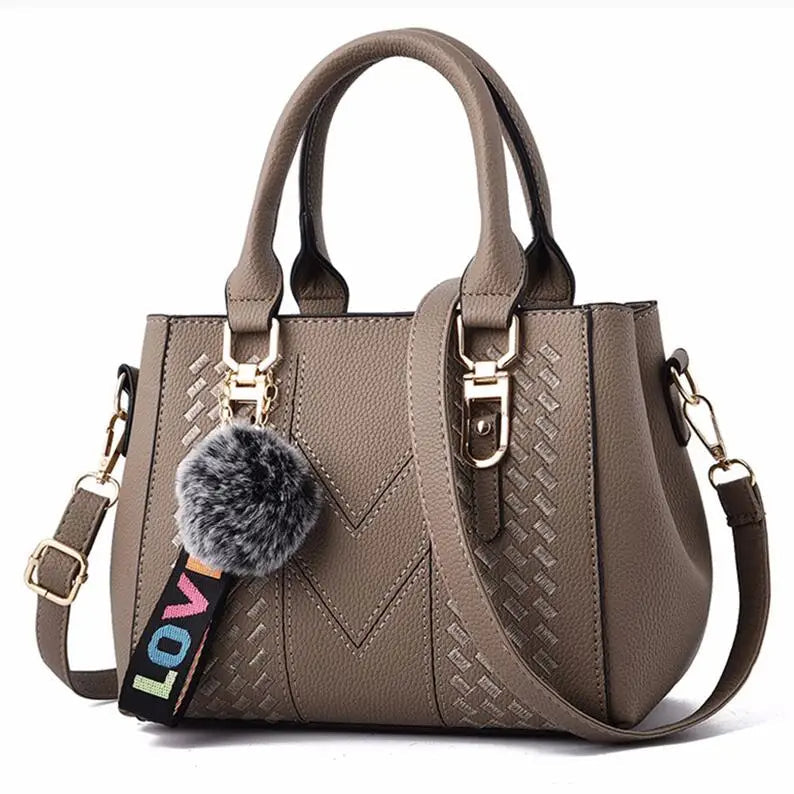 Damenhandtasche aus Leder, beige, mit Schulterriemen und Pompon-Anhänger, modisch und elegant.
