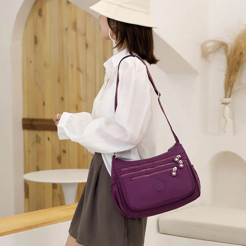 Frau mit lila Umhängetasche, weißer Bluse, beigem Hut; modisches Accessoire, Freizeitkleidung.