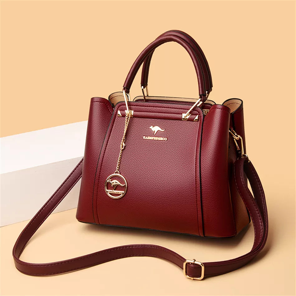 Damenhandtasche aus rotem Leder mit goldenen Details und abnehmbarem Schulterriemen.