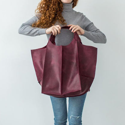 Frau hält große, weinrote Ledertasche, modisches Accessoire, lässiger Stil.