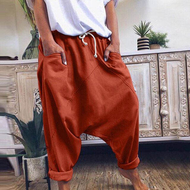 Frau in roten Haremshosen, Boho-Stil, Mid-Waist, lässig, weit geschnitten, Baumwolle.
