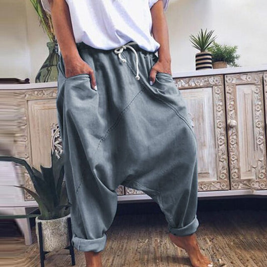 Frau in grauen Haremshosen, Boho-Stil, Mid-Waist, lässig, weites Bein, Baumwolle.