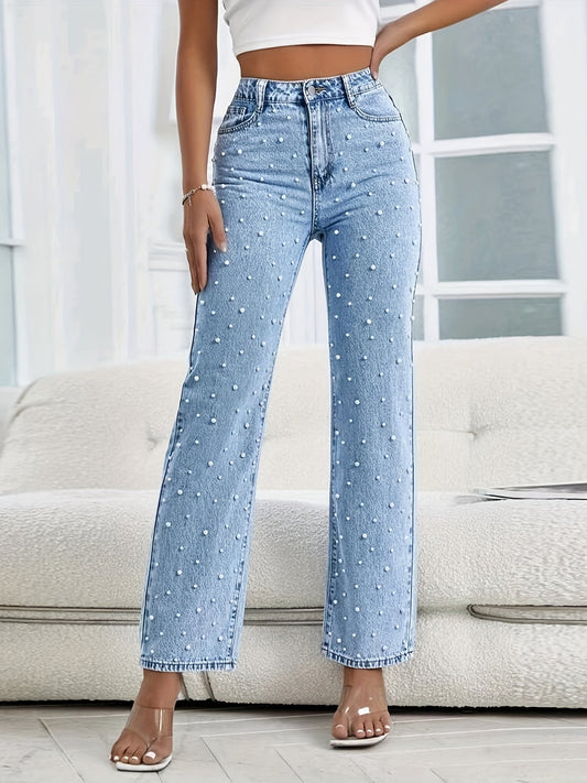 Frau in blauer Jeans mit weißen Punkten, hoher Taille, vor weißem Sofa, modisch, lässig.