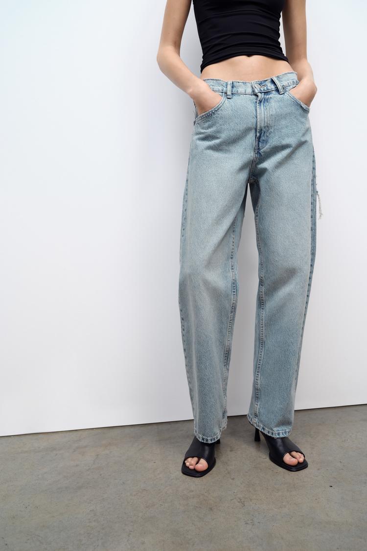Frau in blauer Jeans und schwarzem Top, modische Kleidung, lässiger Stil, Betonboden.