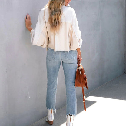 Frau in weißem Pullover und blauer Jeans mit brauner Ledertasche, lässige Mode.