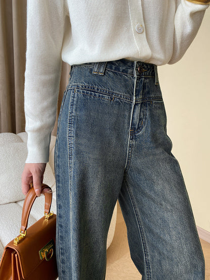 Frau in blauer Jeans und weißem Strickpullover hält braune Ledertasche.