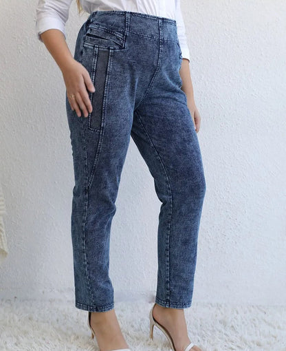 Frau in blauer Jeans mit hoher Taille, seitlichen Taschen, weißem Oberteil, High Heels.