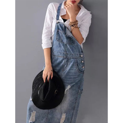 Frau in zerrissener Jeans-Latzhose und weißem Hemd hält schwarzen Hut, modisch, lässig.