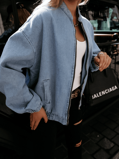 Frau in blauer Jeansjacke, weißem Top, schwarze Tasche, modisch, urbaner Stil.