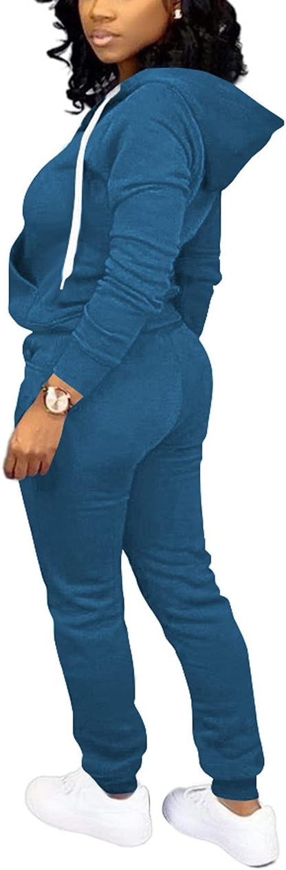 Frau in blauem Jogginganzug mit Kapuze und weißen Sneakern, sportliche Freizeitkleidung.