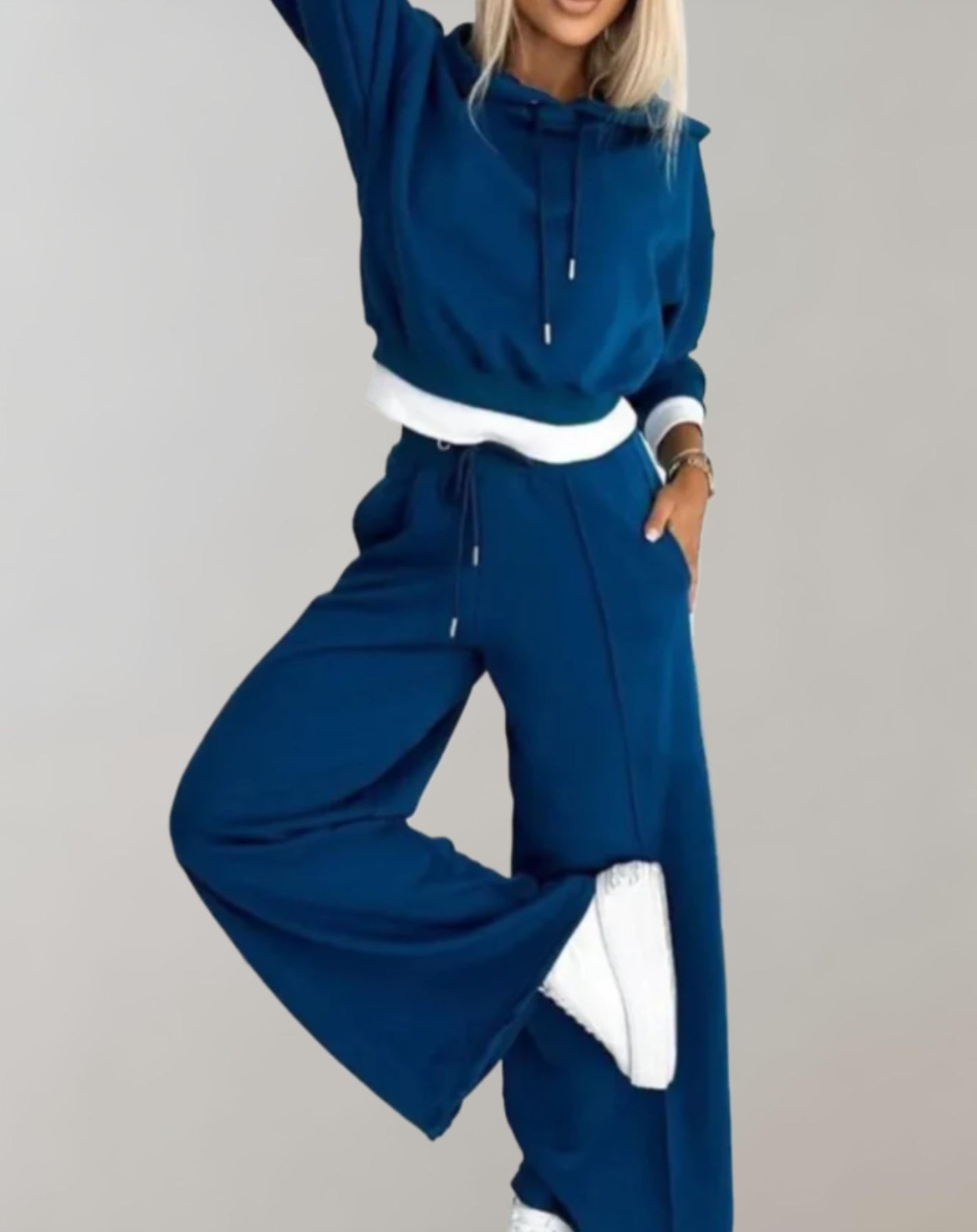 Frau in blauem Jogginganzug, Kapuzenpullover und weite Hose, sportlich, bequem, modisch.