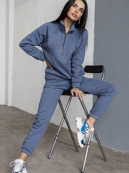 Frau in blauem Jogginganzug auf Stuhl, sportlich, bequem, Freizeitmode, Innenraum.