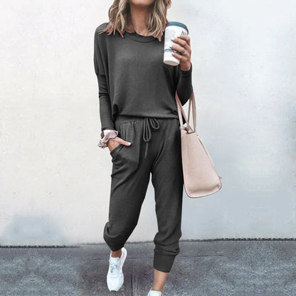 Frau in grauem Jogginganzug mit Kaffeebecher und beiger Tasche, lässige Mode, Straßenstil.