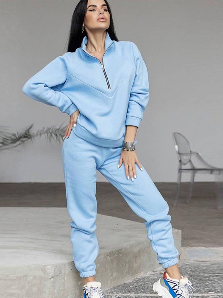 Frau in hellblauem Jogginganzug, Reißverschluss, Freizeitmode, bequem, modern, sportlich.