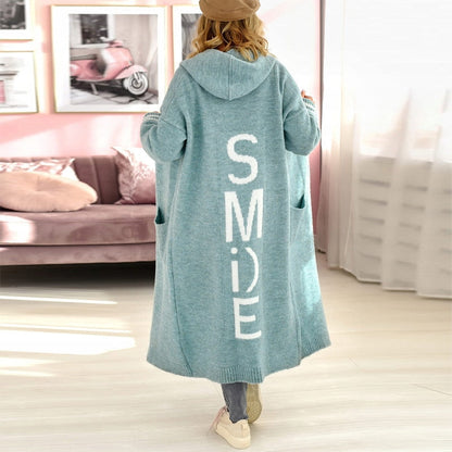 Frau in blauem Kapuzenmantel mit "SMILE"-Aufdruck, lässige Mode, Wohnzimmer.