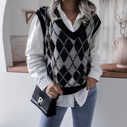 Frau in weißem Hemd und schwarz-weißem Argyle-Pullover, Jeans, schwarze Umhängetasche.