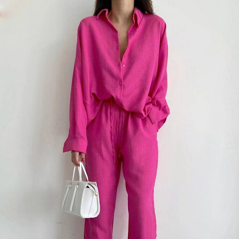 Frau in pinkem Leinen-Set mit Bluse und Hose, weiße Handtasche, modisch, elegant.