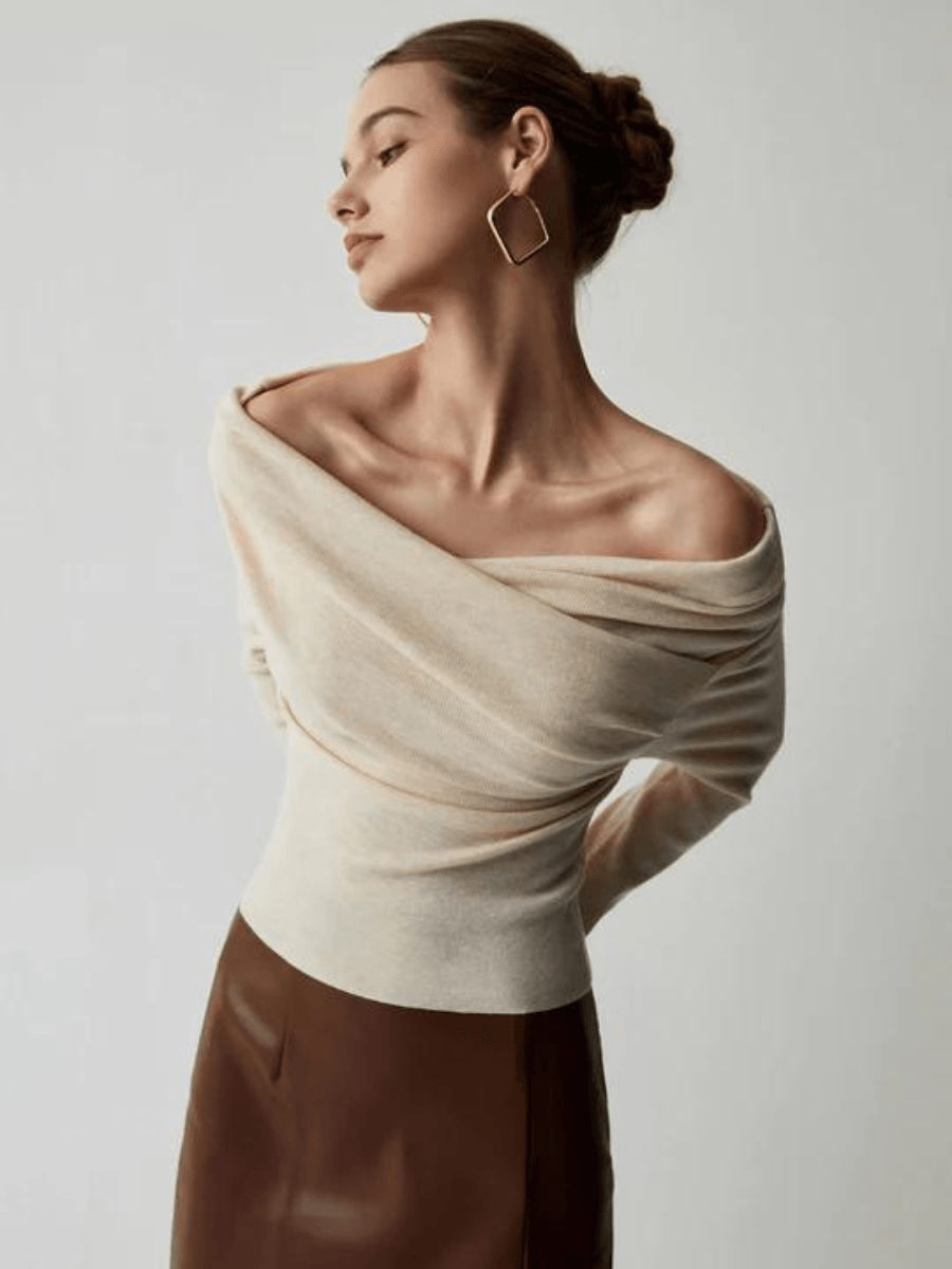 Frau in cremefarbenem Off-Shoulder-Pullover und braunem Rock, elegantes Modeporträt.