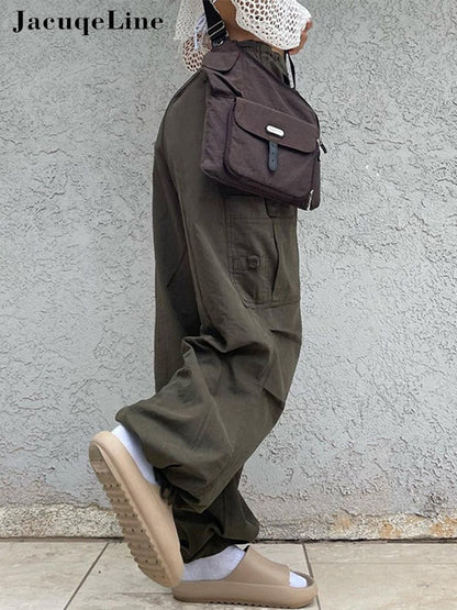 Frau in olivgrüner Cargohose, braune Umhängetasche, beige Sandalen, lässiger Streetwear-Look.