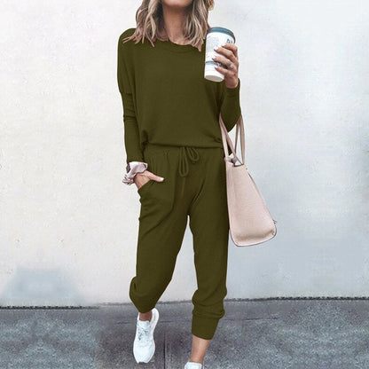 Frau in olivgrünem Freizeitanzug mit Kaffeebecher und beiger Tasche, lässige Mode.