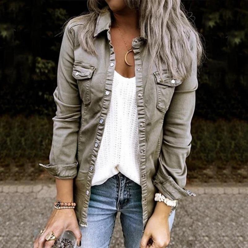 Frau in olivgrüner Jeansjacke, weißem Top und blauer Jeans im Freien.
