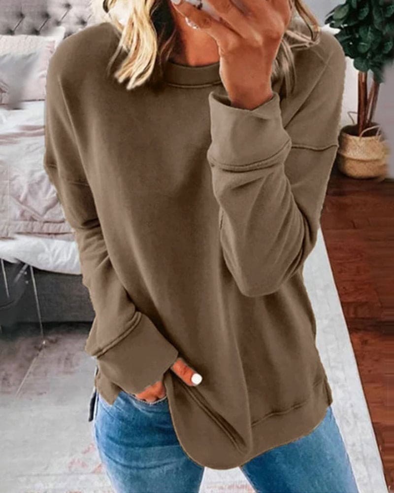 Frau in olivgrünem Sweatshirt und blauer Jeans im Schlafzimmer, lässige Mode.
