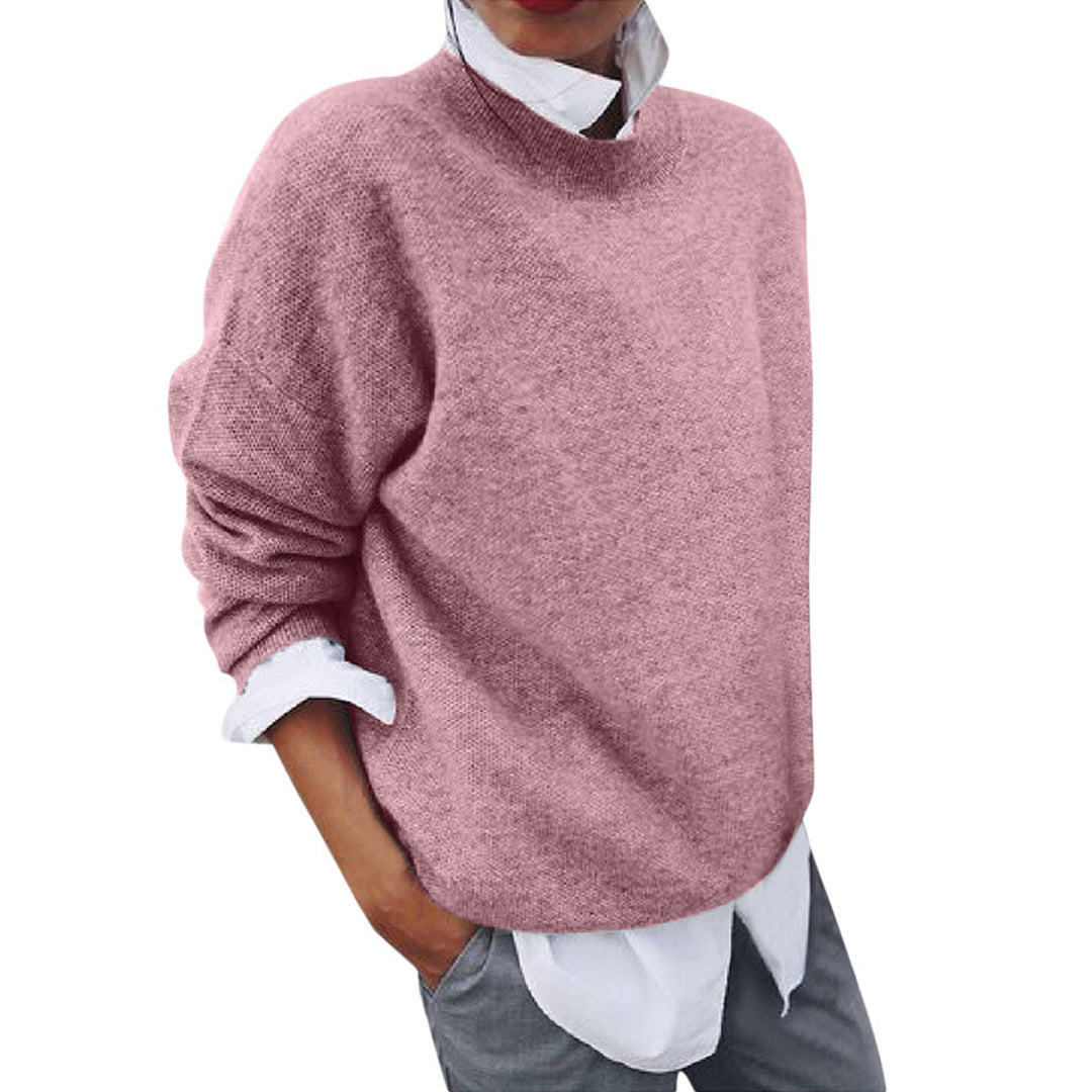 Rosa Damenpullover aus Wolle, lässig geschnitten, über weißem Hemd getragen, modisch elegant.