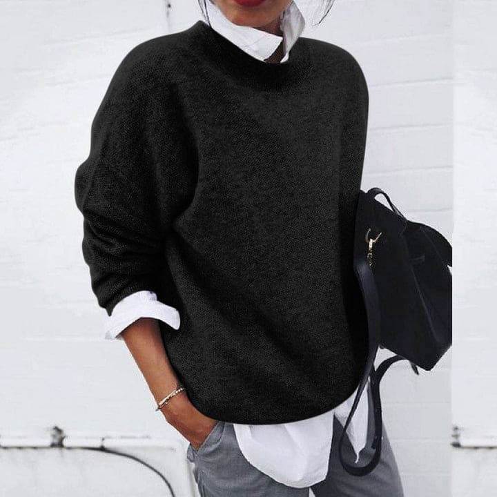 Frau in schwarzem Pullover und weißem Hemd, hält schwarze Tasche, lässiger Herbstlook.