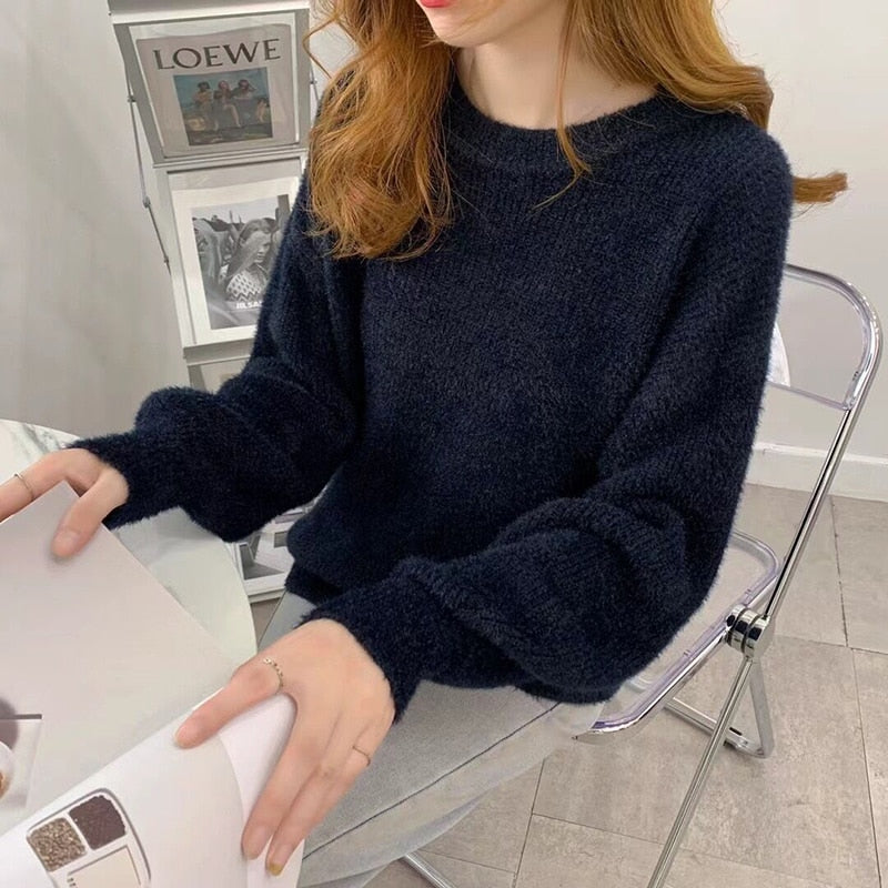 Frau in schwarzem Strickpullover, sitzt an Tisch, modernes Interieur, gemütlicher Look.