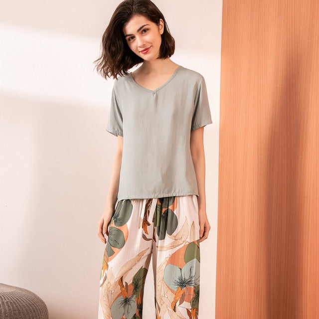 Frau in grauem T-Shirt und gemusterter Hose, lässige Damenmode, Sommeroutfit, Innenraum.
