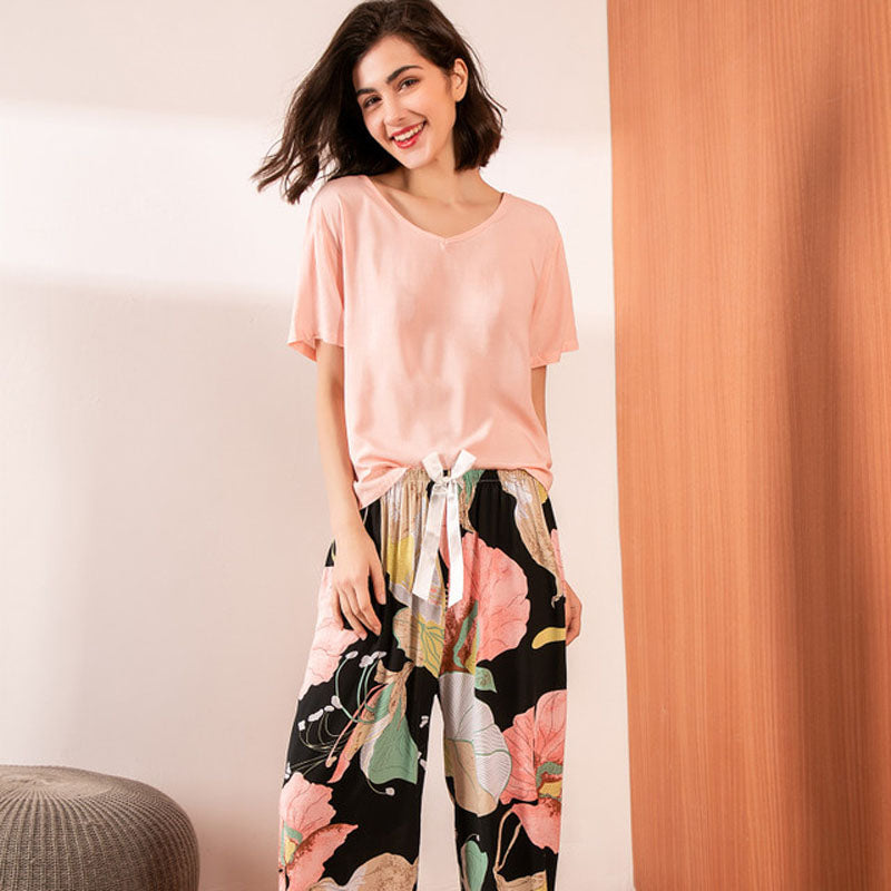 Frau in rosa T-Shirt und bunter Blumenhose, lächelnd, Freizeitmode, Innenaufnahme.