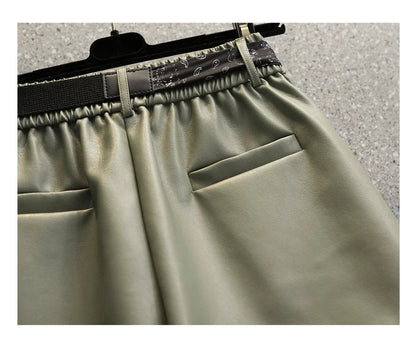 Grüne Lederhose mit elastischem Bund und Taschen, modische Damenbekleidung, Nahaufnahme.
