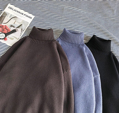 Drei Rollkragenpullover in Braun, Blau und Schwarz auf gestreiftem Hintergrund.