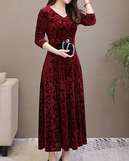 Frau in elegantem, rotem Samtkleid mit Blumenmuster, hält schwarze Clutch, Abendmode.