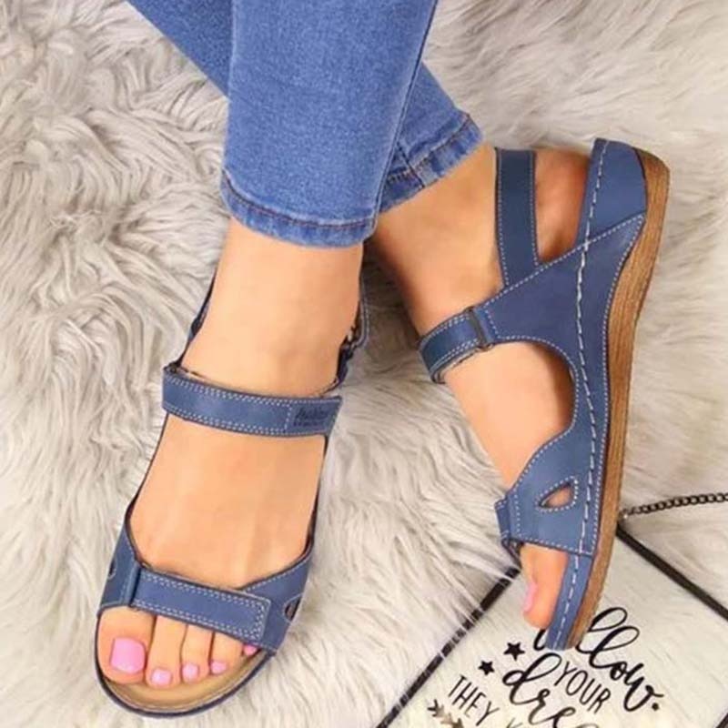 Blaue Damen-Sandalen aus Leder, bequem, mit Klettverschluss, auf grauem Teppich.