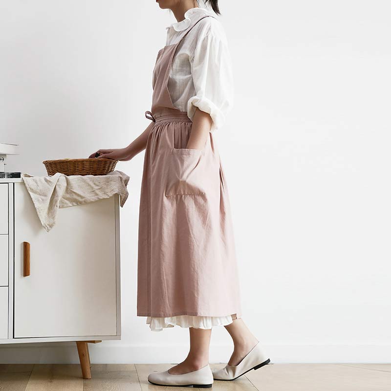 Frau in rosa Baumwollschürze, weißes Hemd, hält Korb, moderne Küchenszene.
