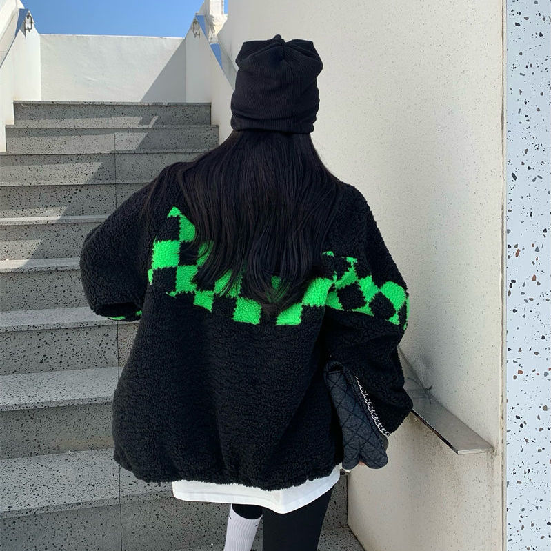 Frau in schwarzer Jacke mit grünem Karomuster, schwarze Mütze, Treppe, modisch, Winterkleidung.